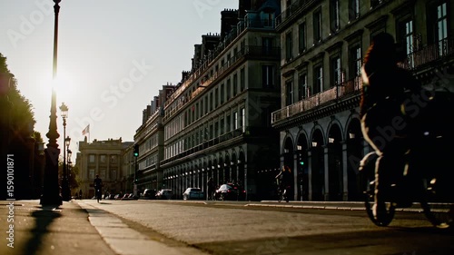 Street life in Paris, France at sunset. Beautiful architecture, silhouettes of people on bicycles walking through the fashion capital.