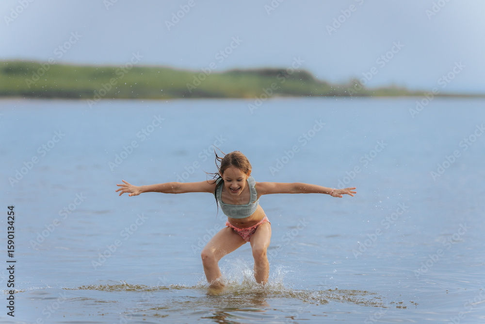 A young girl jumps high above the water in a powerful split pose, splashing below on a bright summer day, capturing motion, freedom, and joy. A young girl jumps high above the water in a powerful split pose, splashing below on a bright summer day, capturing motion, freedom, and joy.