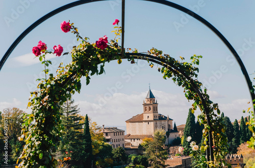 Fairytale view of the Alhambra through a rose-covered archway