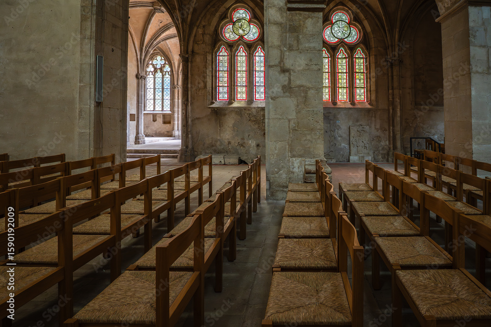Obraz premium A quiet, historic church with wooden pews and colorful stained glass windows. Gothic architecture and the play of light create a venerable, tranquil atmosphere
