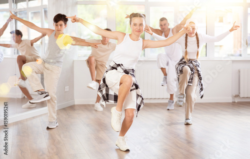 Photography Young girl in bright clothes, together with group of teenage friends, learn to dance hip hop in choreographic hall