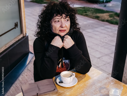 Thoughtful mature woman enjoying a coffee break at outdoor cafe
