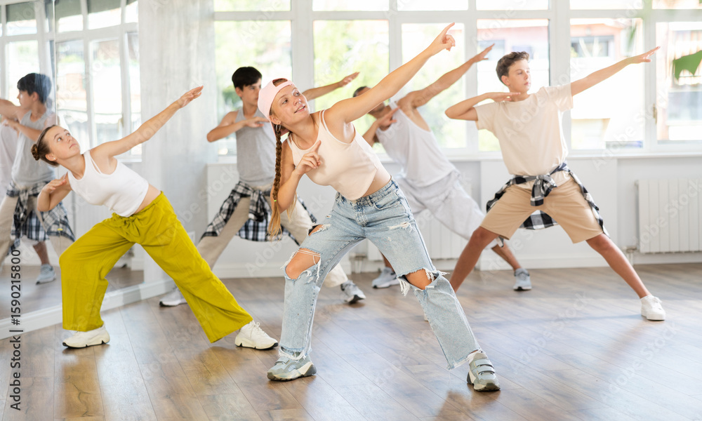 Fototapeta premium Stylishly dressed teenagers learn to dance hip-hop and breakdance in a dance studio