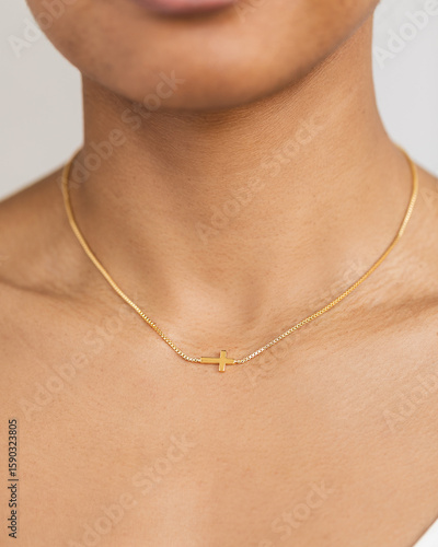 Close up shot of model wearing sideways dainty cross necklace on white background
