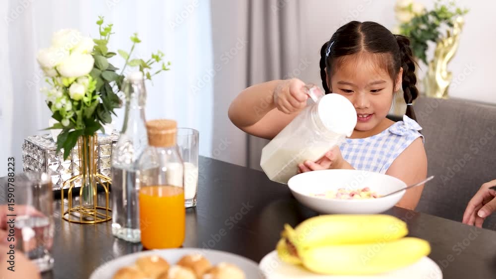 Young Girl Pouring Milk on Cereal at Breakfast Table Young Girl Pouring Milk on Cereal at Breakfast Table