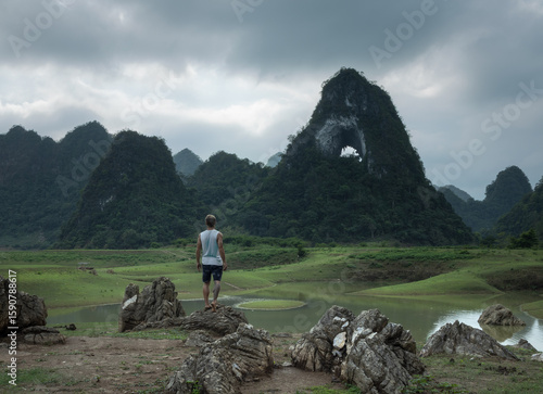 A solo male traveler at the scenic viewpoint on ''Angel's Eye' mountains in picturesque valley of Cao Bang province in northern Vietnam