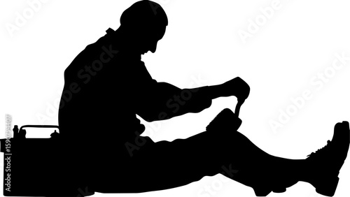 Silhouette of a seated worker with a toolbox and tool in hand doing repairs in a dark monochrome scene