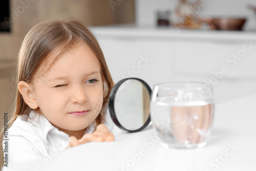Cute little girl magnifying...