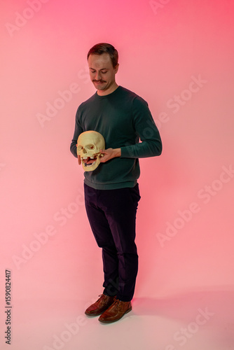 man looks at human skull