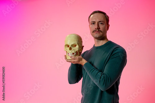 man holds up skull