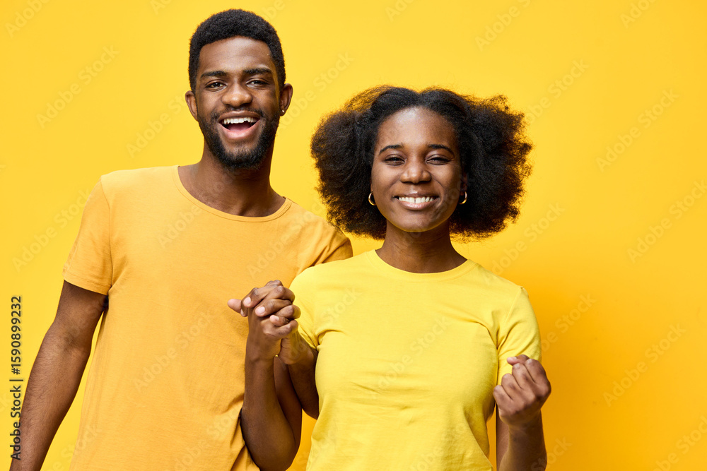 Fototapeta premium Happy African American couple wearing yellow shirts, expressing joy and positivity against a bright yellow background, perfect for lifestyle and relationship themes
