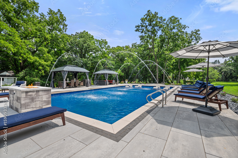 Obraz premium Luxury pool house with water fountain feature and stunning setup under clear blue sky