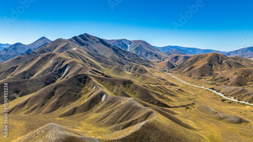 Aerial view of the alpine pass road winding its way through the arid mountain ranges at the Lindis Pass summit