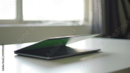 Wallpaper Mural Minimalist Workspace Close-Up of Sleek Laptop Partially Open on Clean White Table, Natural Light from Window Torontodigital.ca