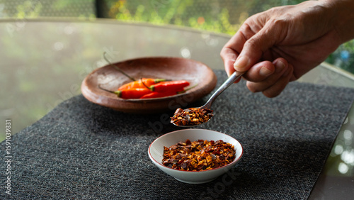 Obraz na płótnie people hand holding chili flakes, red pepper flakes, using a tablespoon