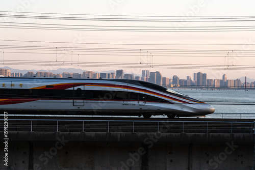 Under the setting sun, high-speed trains run through the modern urban area, embodying the concepts of urban speed and transportation