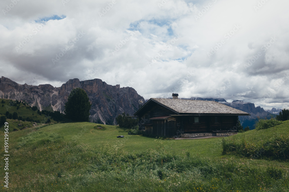 A charming wooden cabin nestled in the breathtaking Dolomites mountains on a cloudy day. A charming wooden cabin nestled in the breathtaking Dolomites mountains on a cloudy day.