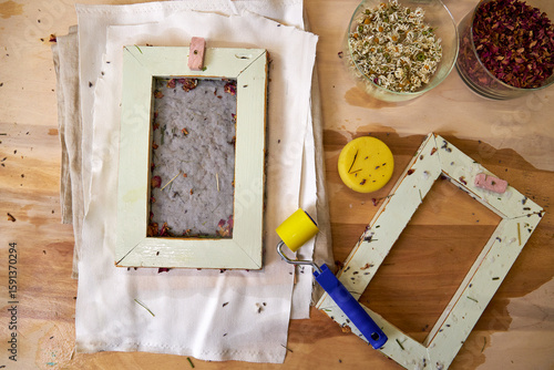 Freshly pressed handmade paper with dried rose petals and herbs, laid on fabric to dry. DIY botanical papermaking using traditional frame and natural floral ingredients