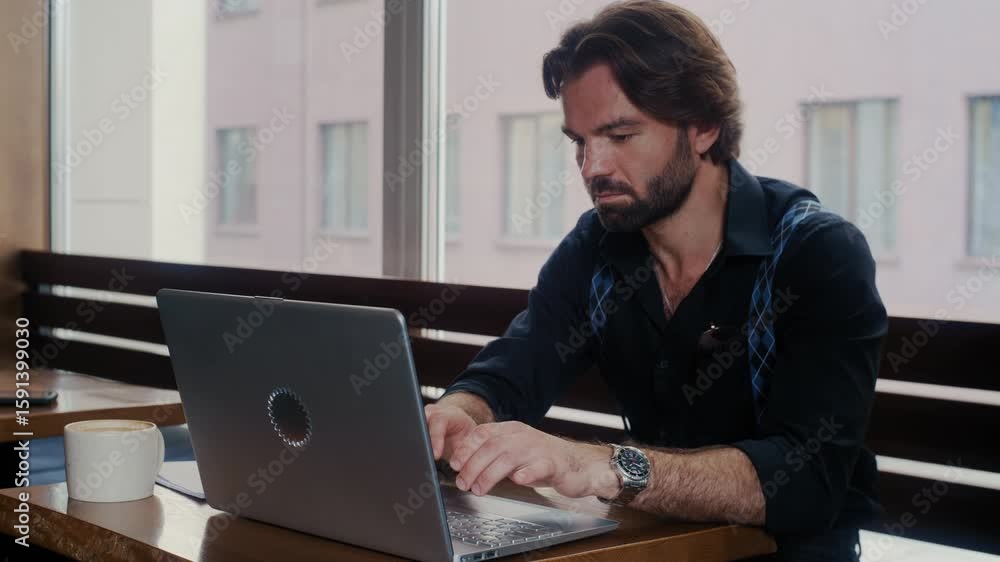 Professional man working remotely from a coffee shop, focused on his laptop and handwritten notes while enjoying a cup of coffee. Professional man working remotely from a coffee shop, focused on his laptop and handwritten notes while enjoying a cup of coffee.