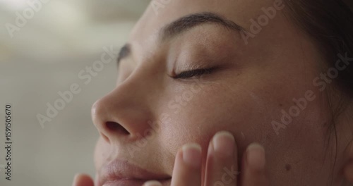 Young woman applying cream to her face