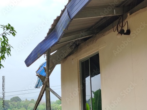 Corrugated metal roof sheeting lifted and bent by high winds from a recent tropical storm.
