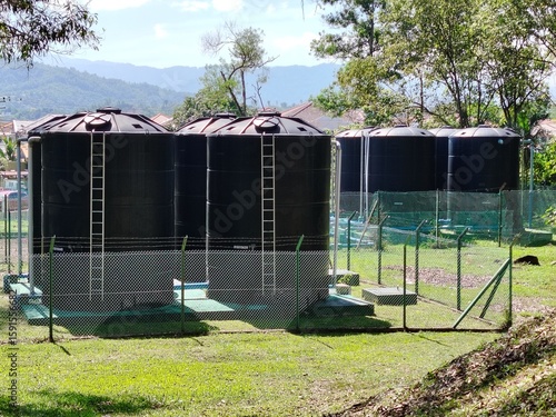 Essential utilities elevated view of protected water storage facility surrounded by chain link and green grass.