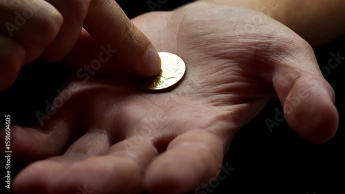An American cent is in the hands of a guy.
A man holds a metal coin in his hands close-up on a black background.
A man puts a sept. on his hand.
Financial problems and inflation