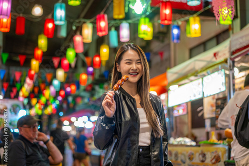Fototapet Asian woman enjoying street food at Chiang Mai Walking Street Night Bazaar