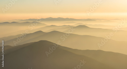 Misty Mountain Range at Sunrise with Golden Hues in the Sky	