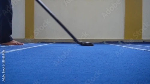 A man vacuums the carpet in the room using a vacuum cleaner.