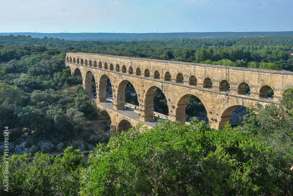 Fototapeta premium Ancient Roman aqueduct Pont du Gard crossing a lush green valley in southern France, viewed from above