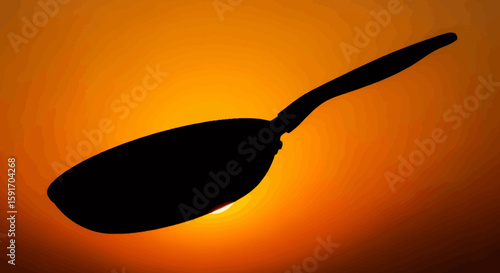 Silhouette of a frying pan against a vibrant sunset backdrop.