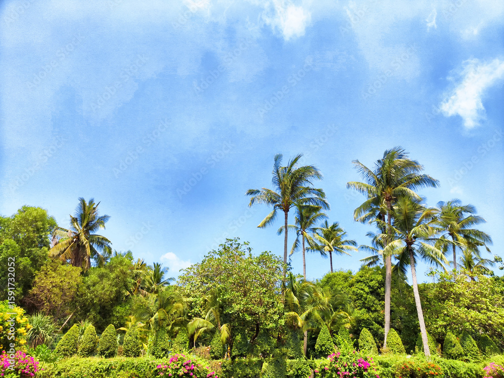 Fototapeta premium Lush tropical garden with palm trees under bright blue sky on a sunny day