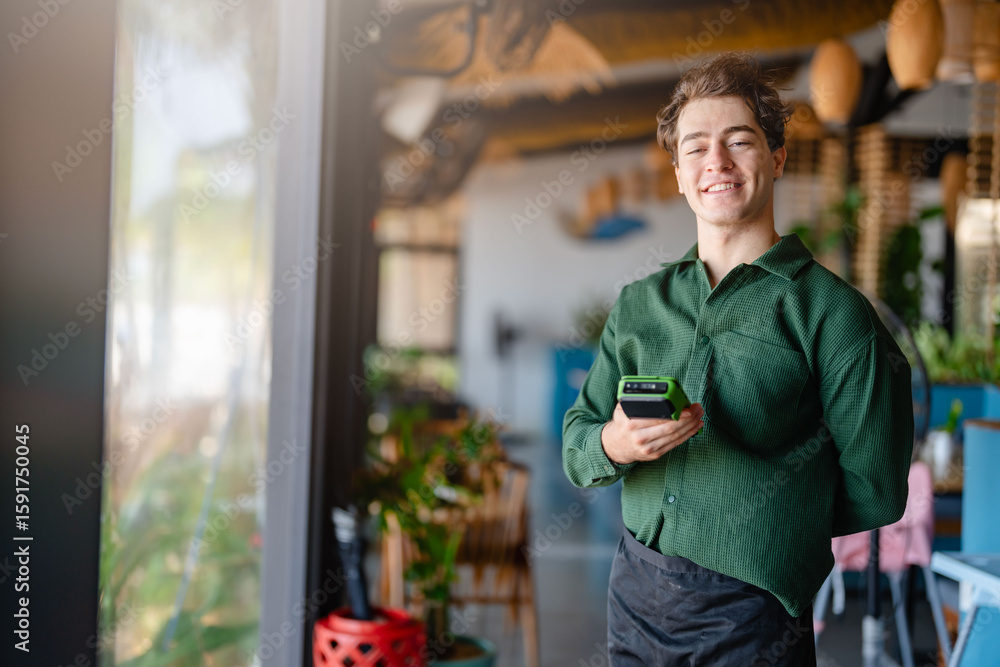 © lordn - Smiling young entrepreneur or waiter holding wireless POS device in a trendy small business cafe, representing modern hospitality © lordn - Smiling young entrepreneur or waiter holding wireless POS device in a trendy small business cafe, representing modern hospitality