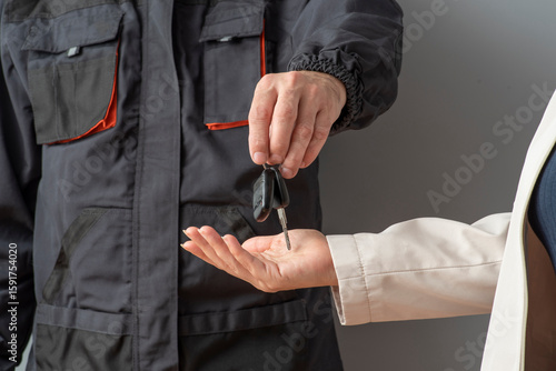 Fotografía Hand of a male fixer mechanic in coveralls passing car keys to a woman's hand