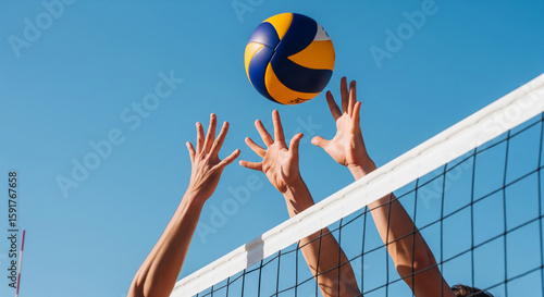 Dynamic shot of volleyball players blocking a ball over the net against a clear blue sky, ideal for sports, action, and outdoor activity themes