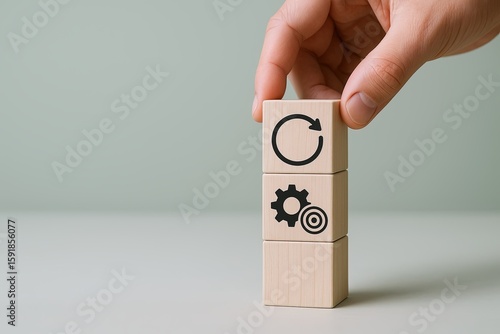 Hand holding wooden blocks with gear and target icons representing process and goal concepts.