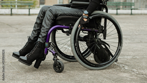 Fashionable person in wheelchair on concrete surface, showcasing strength and independence