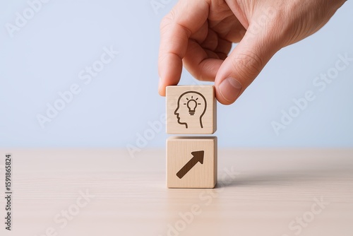 Hand holding wooden blocks with lightbulb and upward arrow symbols on a light background.