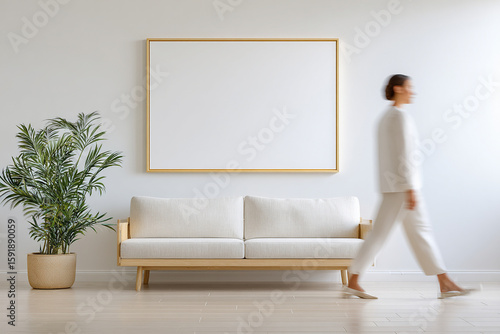 Minimalist living room with a person walking past a white sofa and blank wall art, showcasing a serene and modern home interior