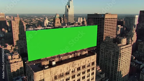 Aerial View of Large Green Screen Billboard on Rooftop in Bustling Cityscape at Golden Hour, Ready for Custom Advertising Content