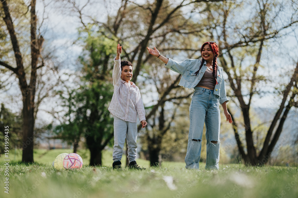 Fototapeta premium Cheerful mother and her child share a playful moment enjoying the outdoors in a scenic park. The sunny day provides a beautiful backdrop of trees and greenery, emphasizing family fun and togetherness.