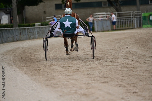 Trabrennfahrer auf Sulky auf der Rennbahn beim Aufwärmen, Rückenansicht