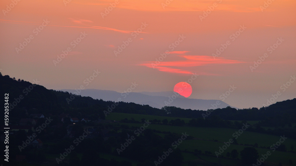 Obraz premium Red Sunrise with Sun Disk Rising Above Hilly Horizon in Czech Landscape