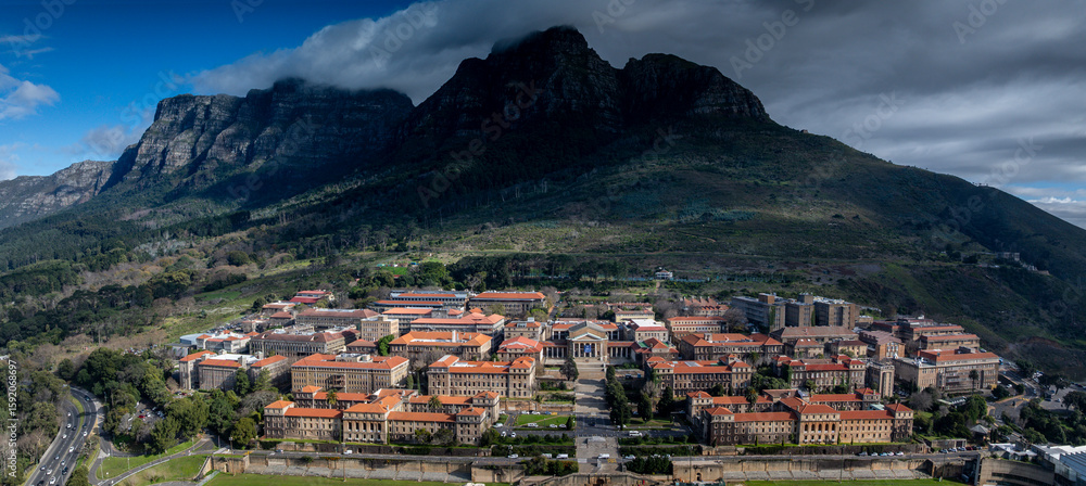 Fototapeta premium Panoramic aerial view of the University of Cape Town campus, with the Sarah Baartman Hall in centre. Table Mountain's Devil Peak in backbround.