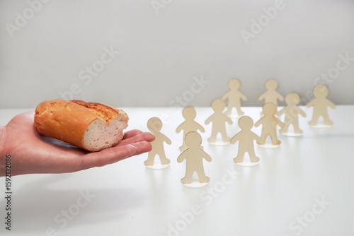 Canvas Print Hand extends or gives a piece of bread to the figures of people