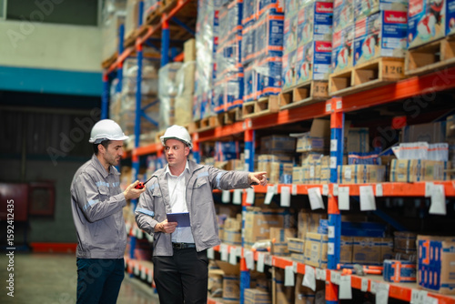 Engineers using digital tools to manage logistics in a storage aisle. Excellent for freight service, inventory systems, and logistics workflow promotion.