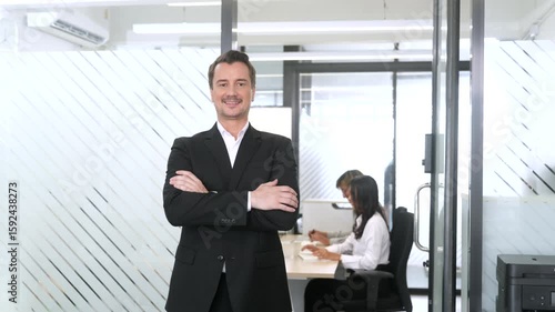 Confident business leader standing with arms crossed in a modern office, representing authority and success in a professional environment