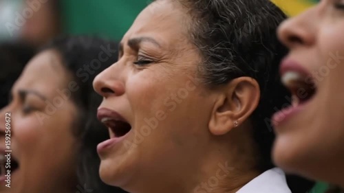 Close up of a woman singing with a brazilian flag in the background with another person visible