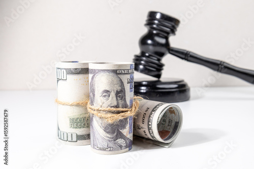 Fotografie A gavel set behind bundles of money conveys the concept of financial consequences, court verdicts, or legal disputes involving monetary resolutions